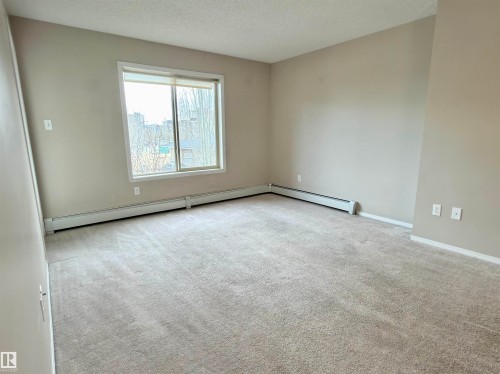 This room features light-colored walls and soft carpeting throughout - 205 11816 22 Avenue, Edmonton, AB - Indoor Photo Showing Other Room