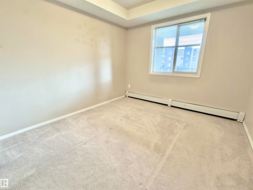 This room features neutral-toned walls, carpeted flooring, and a window with blinds - 205 11816 22 Avenue, Edmonton, AB - Indoor Photo Showing Other Room