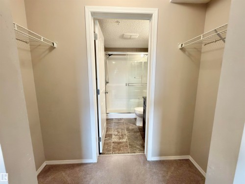 The property features a closet with wire shelving and carpeting, leading to an ensuite bathroom. - 205 11816 22 Avenue, Edmonton, AB - Indoor