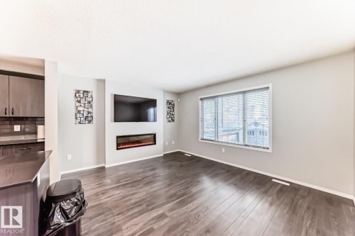 Unfurnished living room with dark wood-type flooring and a glass covered fireplace - 2823 Duke Crescent, Edmonton, AB - Indoor With Fireplace
