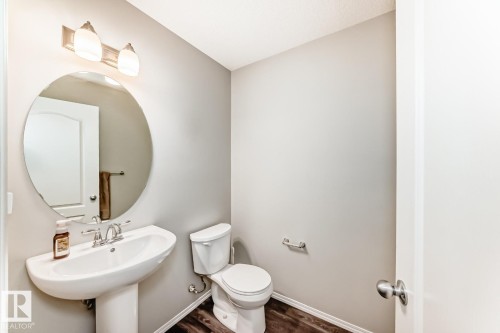 Half bathroom featuring toilet and dark wood-style flooring - 2823 Duke Crescent, Edmonton, AB - Indoor Photo Showing Bathroom