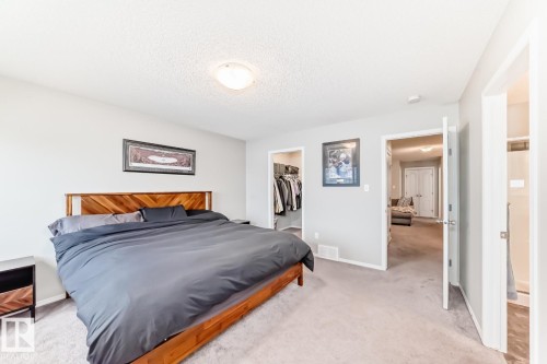 Bedroom featuring light carpet, a spacious closet, and a textured ceiling - 2823 Duke Crescent, Edmonton, AB - Indoor Photo Showing Bedroom