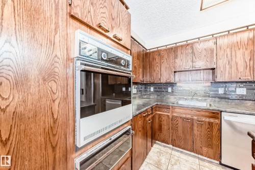 Kitchen with white dishwasher, a warming drawer, a textured ceiling, light tile patterned flooring, and decorative backsplash - 38 Lancaster Crescent, St. Albert, AB - Indoor Photo Showing Kitchen