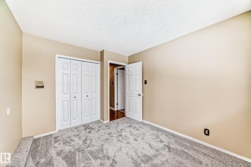 Unfurnished bedroom featuring carpet flooring, a textured ceiling, and a closet - 38 Lancaster Crescent, St. Albert, AB - Indoor