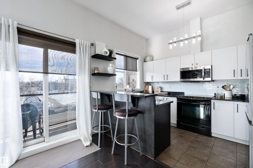 Recently renovated kitchen  with a kitchen breakfast bar, black electric range, open shelves, backsplash, and stainless steel microwave - 302 10905 109 Street, Edmonton, AB - Indoor Photo Showing Kitchen With Upgraded Kitchen