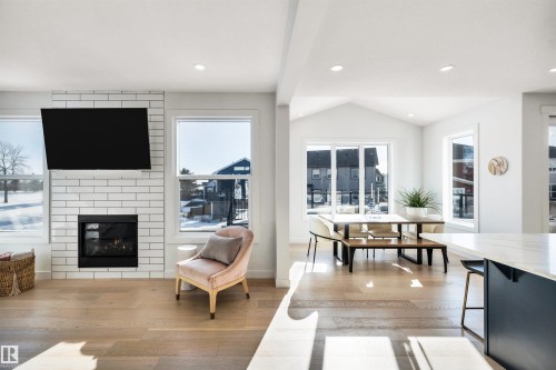Living room featuring light wood finished floors, a fireplace, recessed lighting, and vaulted ceiling - 11 Promenade Point(E), Beaumont, AB - Indoor Photo Showing Other Room With Fireplace