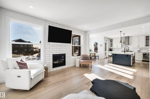 Living area with light wood-style floors, a fireplace, beverage cooler, plenty of natural light, and recessed lighting - 11 Promenade Point(E), Beaumont, AB - Indoor Photo Showing Living Room With Fireplace
