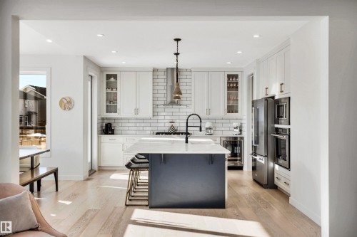 Kitchen featuring pendant lighting, dual tone cabinets, a kitchen bar, glass insert cabinets, and a center island with sink - 11 Promenade Point(E), Beaumont, AB - Indoor Photo Showing Kitchen With Upgraded Kitchen
