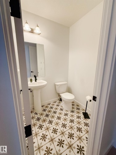 Half bathroom with a textured ceiling and light tile patterned floors - 11 Promenade Point(E), Beaumont, AB - Indoor Photo Showing Bathroom