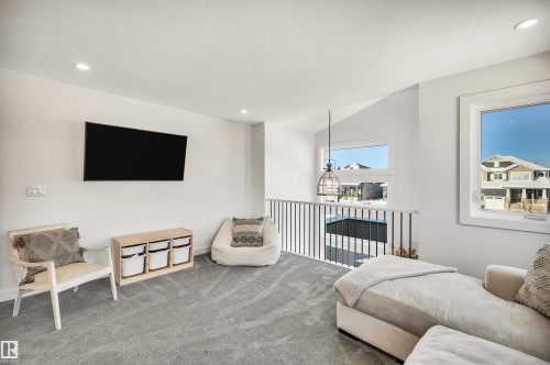 Carpeted living room featuring recessed lighting and vaulted ceiling - 11 Promenade Point(E), Beaumont, AB - Indoor