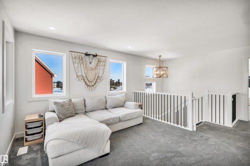 Carpeted living room with hanging lights and baseboards - 11 Promenade Point(E), Beaumont, AB - Indoor Photo Showing Living Room