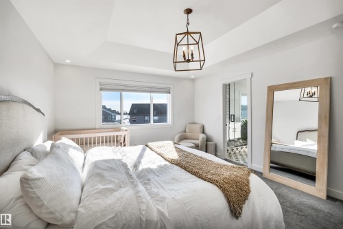 Carpeted bedroom with suspended lighting and a tray ceiling - 11 Promenade Point(E), Beaumont, AB - Indoor Photo Showing Bedroom