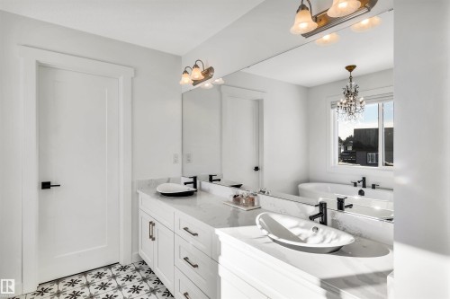Full bath with double vanity, a freestanding tub, and a chandelier - 11 Promenade Point(E), Beaumont, AB - Indoor Photo Showing Bathroom