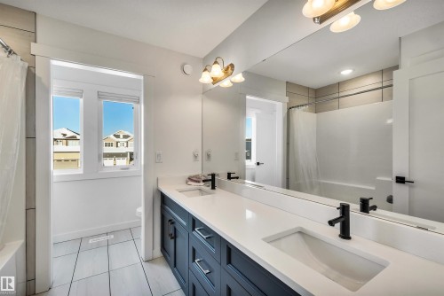 Full bathroom with shower / bathtub combination with curtain, double vanity, and light tile patterned floors - 11 Promenade Point(E), Beaumont, AB - Indoor Photo Showing Bathroom