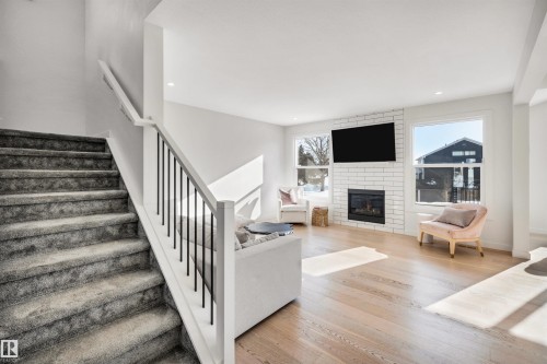 Stairway featuring wood finished floors, a fireplace, and recessed lighting - 11 Promenade Point(E), Beaumont, AB - Indoor With Fireplace