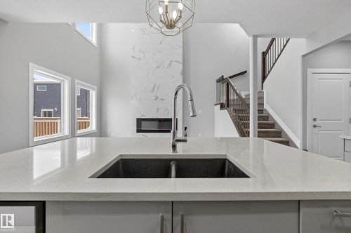 Kitchen with light stone counters, hanging lights, and a high ceiling - 3224 160 Street, Edmonton, AB - Indoor Photo Showing Kitchen With Double Sink