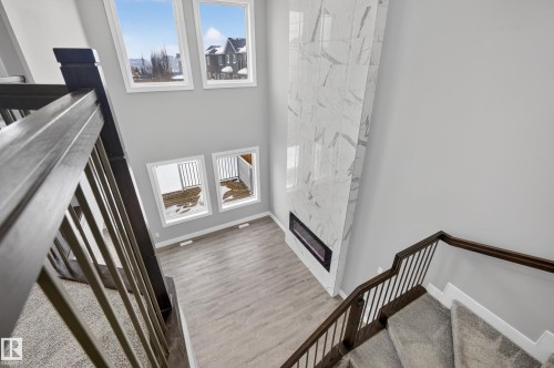 Staircase featuring plenty of natural light, a high ceiling, a premium fireplace, and wood finished floors - 3224 160 Street, Edmonton, AB - Indoor Photo Showing Other Room