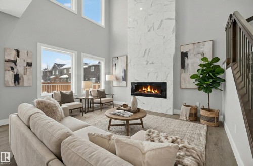 Living area with wood finished floors, a premium fireplace, a high ceiling, and healthy amount of natural light - 3224 160 Street, Edmonton, AB - Indoor Photo Showing Living Room With Fireplace