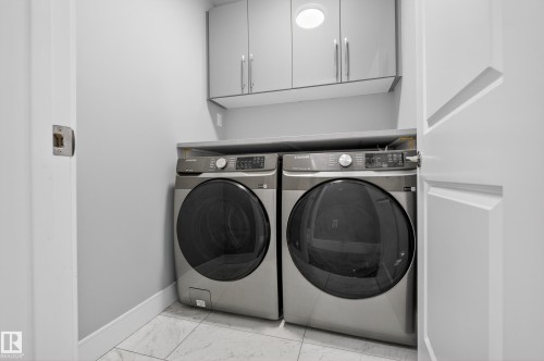 Laundry room featuring cabinet space, washer and dryer, and light marble finish floors - 3224 160 Street, Edmonton, AB - Indoor Photo Showing Laundry Room