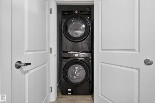 Laundry area with stacked washer and dryer and light wood-style floors - 3224 160 Street, Edmonton, AB - Indoor Photo Showing Laundry Room
