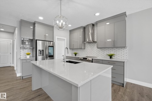 Kitchen with gray cabinets, a kitchen island with sink, stainless steel appliances, decorative backsplash, and a chandelier - 3224 160 Street, Edmonton, AB - Indoor Photo Showing Kitchen With Upgraded Kitchen