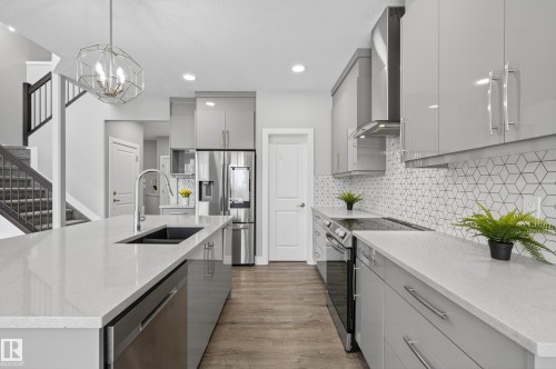 Kitchen featuring stainless steel appliances, modern cabinets, dark wood-type flooring, light stone counters, and two tone cabinets - 3224 160 Street, Edmonton, AB - Indoor Photo Showing Kitchen With Double Sink With Upgraded Kitchen
