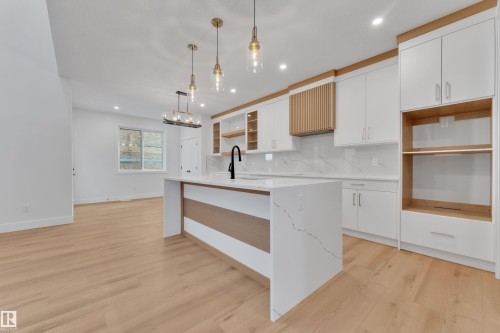 Kitchen with white cabinets, open shelves, light wood-style flooring, light stone counters, and suspended lighting - 6111 Crawford Drive, Edmonton, AB - Indoor Photo Showing Kitchen With Upgraded Kitchen