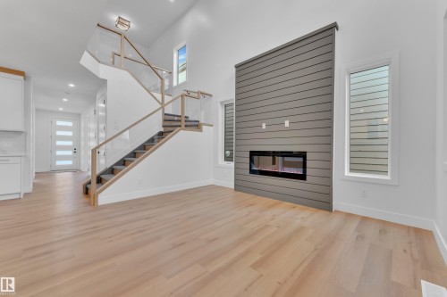 Unfurnished living room with a high ceiling, light wood finished floors, recessed lighting, and a glass covered fireplace - 6111 Crawford Drive, Edmonton, AB - Indoor With Fireplace