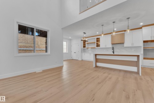 Unfurnished living room featuring light wood-style flooring, a high ceiling, and a chandelier - 6111 Crawford Drive, Edmonton, AB - Indoor Photo Showing Other Room