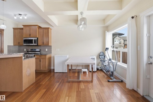 Kitchen featuring wood finish cabinetry, dark stone counters, stainless steel appliances, tasteful backsplash, and dark wood-type flooring - 2923 16 Street, Edmonton, AB - Indoor Photo Showing Kitchen