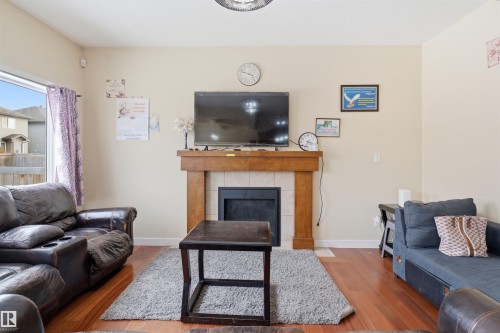 Living area with wood finished floors and a tiled fireplace - 2923 16 Street, Edmonton, AB - Indoor Photo Showing Living Room With Fireplace
