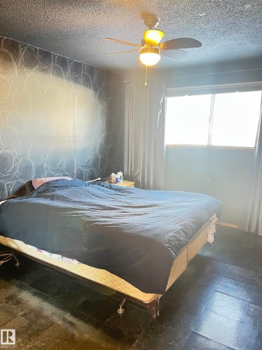Bedroom with stone tile floors, ceiling fan, a textured ceiling, and wallpapered walls - 15003 81 Street, Edmonton, AB - Indoor Photo Showing Bedroom