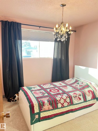 Bedroom featuring carpet, a textured ceiling, multiple windows, and hanging lights - 15003 81 Street, Edmonton, AB - Indoor Photo Showing Bedroom