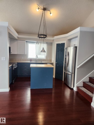 Kitchen with a kitchen island, light countertops, stainless steel appliances, a textured ceiling, and hanging light fixtures - 14076 152 Avenue, Edmonton, AB - Indoor Photo Showing Kitchen With Stainless Steel Kitchen