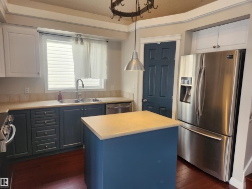 Kitchen featuring stainless steel appliances, a center island, light countertops, hanging light fixtures, and dark wood-type flooring - 14076 152 Avenue, Edmonton, AB - Indoor Photo Showing Kitchen With Stainless Steel Kitchen With Double Sink