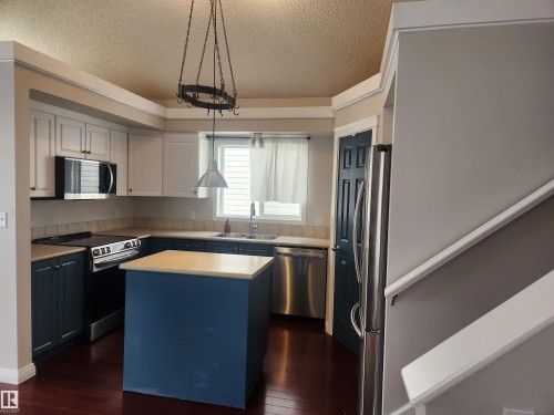 Kitchen with light countertops, stainless steel appliances, a textured ceiling, a center island, and pendant lighting - 14076 152 Avenue, Edmonton, AB - Indoor Photo Showing Kitchen With Stainless Steel Kitchen