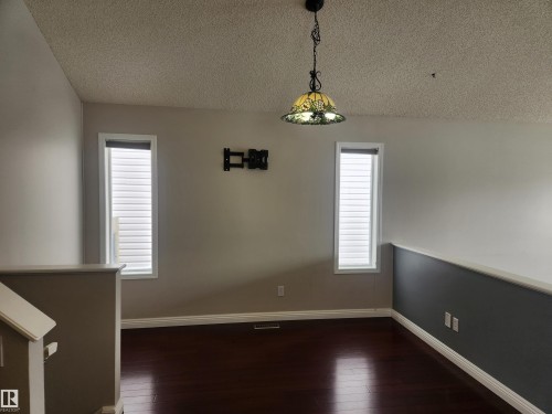 Unfurnished dining area featuring a textured ceiling and dark wood-style flooring - 14076 152 Avenue, Edmonton, AB - Indoor Photo Showing Other Room