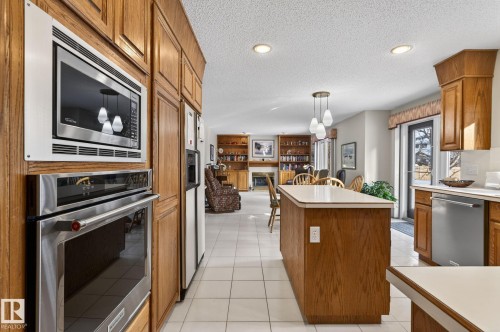 Kitchen with wood finish cabinets, hanging light fixtures, stainless steel appliances, light countertops, and light tile patterned floors - 313 Hedley Way, Edmonton, AB - Indoor Photo Showing Kitchen