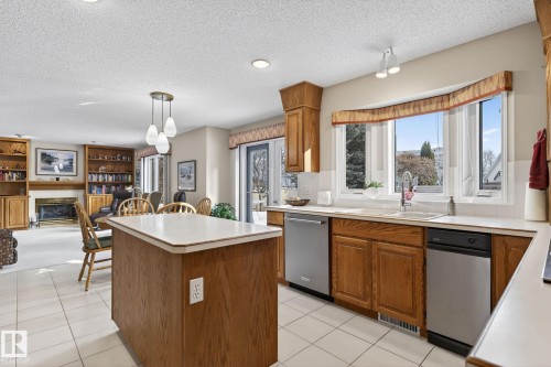 Kitchen featuring wood finish cabinetry, a center island, light countertops, decorative light fixtures, and a textured ceiling - 313 Hedley Way, Edmonton, AB - Indoor Photo Showing Kitchen