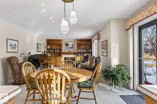 Dining room featuring a fireplace, a textured ceiling, and light tile patterned flooring - 313 Hedley Way, Edmonton, AB - Indoor Photo Showing Dining Room