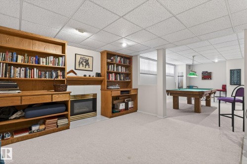 Recreation room with a tile fireplace, light colored carpet, pool table, and a drop ceiling - 313 Hedley Way, Edmonton, AB - Indoor