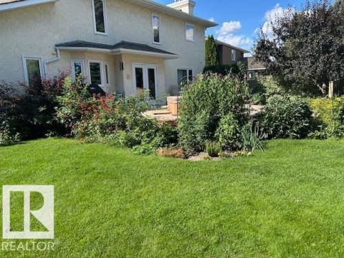Rear view of property with stucco siding, a yard, a chimney, and french doors - 313 Hedley Way, Edmonton, AB - Outdoor