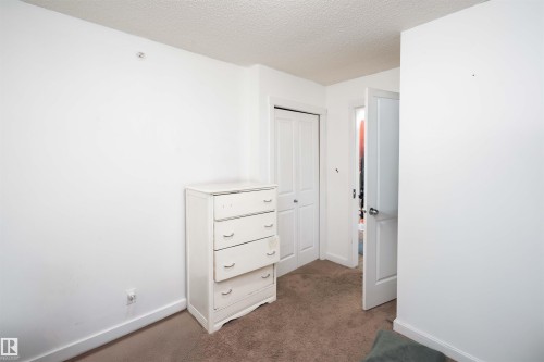Unfurnished bedroom with a textured ceiling, carpet, and a closet - 415 111 Watt Common, Edmonton, AB - Indoor Photo Showing Other Room