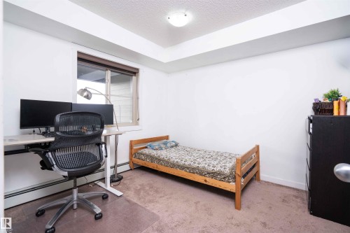 Bedroom with light colored carpet, a desk, a textured ceiling, and baseboard heating - 415 111 Watt Common, Edmonton, AB - Indoor