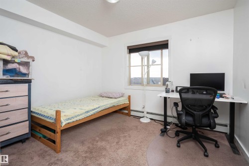 Bedroom with light colored carpet, a desk, a textured ceiling, and a baseboard heating unit - 415 111 Watt Common, Edmonton, AB - Indoor Photo Showing Bedroom