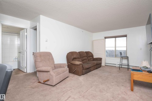 Living room featuring carpet, a textured ceiling, and a baseboard heating unit - 415 111 Watt Common, Edmonton, AB - Indoor