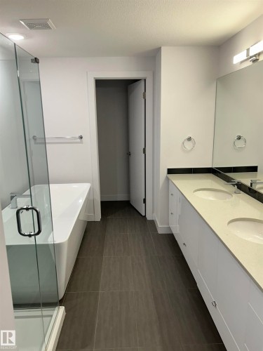 Full bathroom with double vanity, a soaking tub, a shower stall, and a textured ceiling - 202 8510 90 Street, Edmonton, AB - Indoor Photo Showing Bathroom