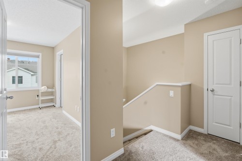 Corridor featuring light carpet, an upstairs landing, and a textured ceiling - 48 1140 Chappelle Boulevard, Edmonton, AB - Indoor Photo Showing Other Room