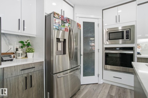 Kitchen featuring stainless steel appliances, white cabinetry, modern cabinets, and light wood-style floors - 1532 37C Avenue, Edmonton, AB - Indoor Photo Showing Kitchen With Stainless Steel Kitchen With Upgraded Kitchen