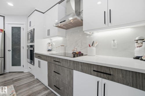 Kitchen featuring exhaust hood, white cabinetry, modern cabinets, decorative backsplash, and appliances with stainless steel finishes - 1532 37C Avenue, Edmonton, AB - Indoor Photo Showing Kitchen With Upgraded Kitchen